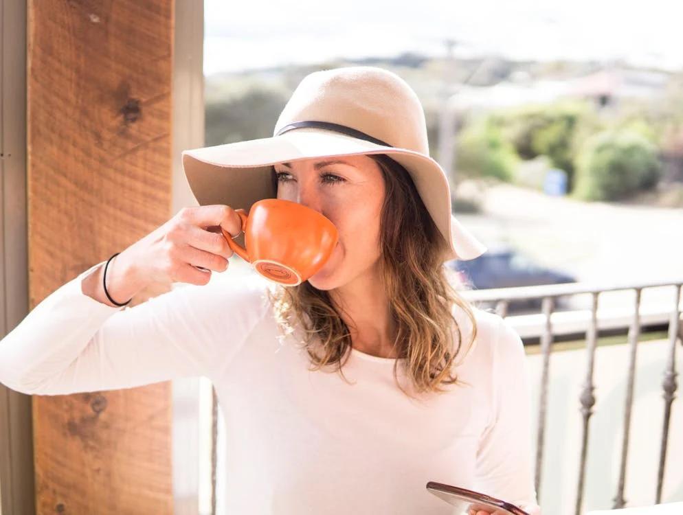 a girl wearing a hat drinking tea from a cup