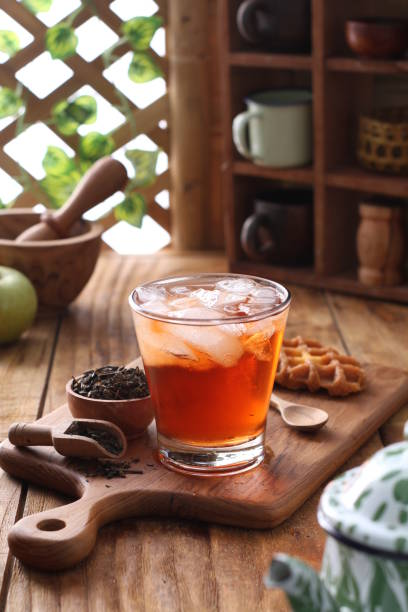 A glass of loose leaf iced tea on a wooden board