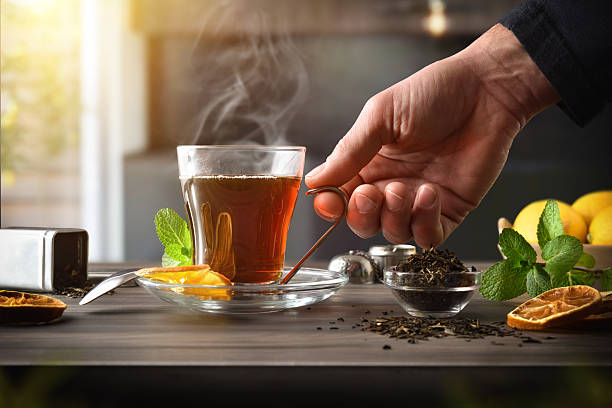 Hand holding a glass cup of steaming loose leaf tea