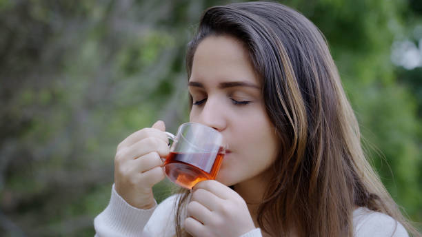 young woman drinking a cup of hibiscus hot tea at outdoors