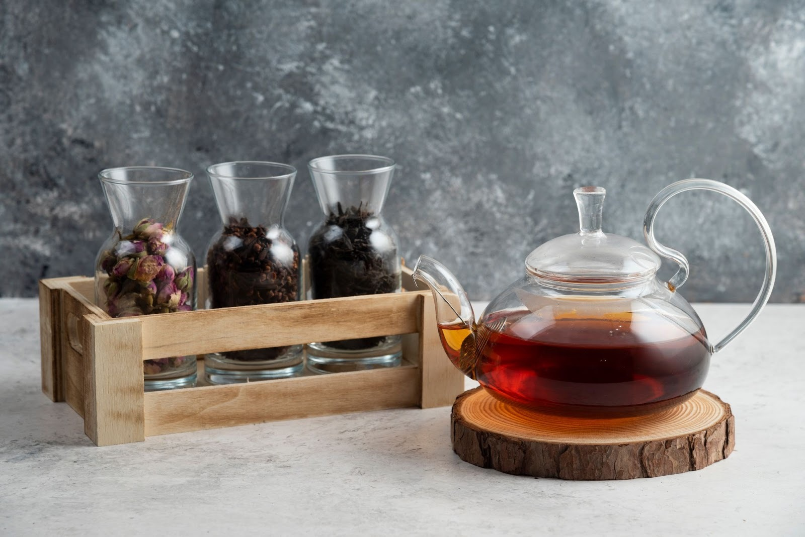 Glass teapot with brewed herbal tea beside jars