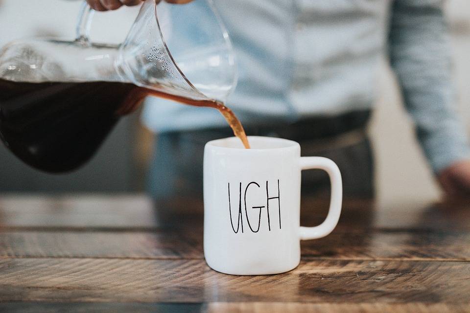 black tea is poured form a clear carafe into a white mug