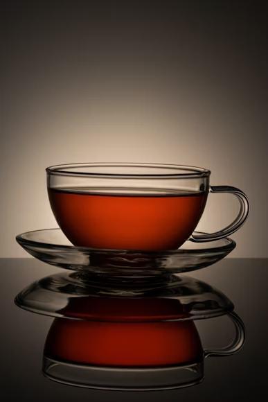 A transparent glass teacup with reddish-brown tea