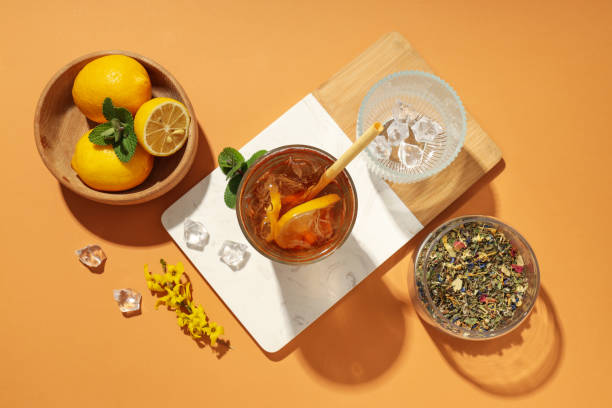 Glass of Iced tea with lemon, mint, and loose tea leaves.
