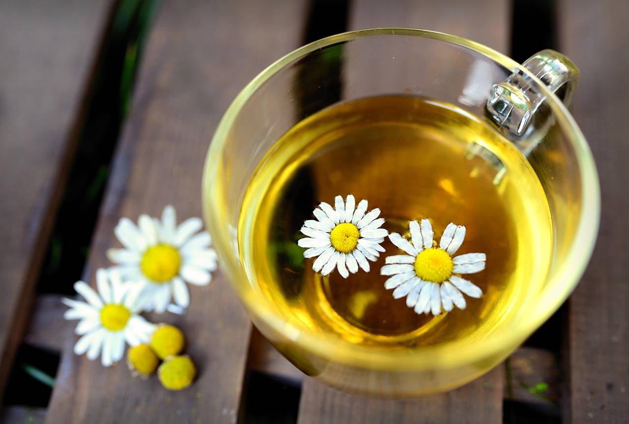 A clear glass cup of golden chamomile tea