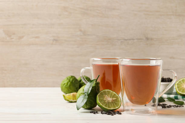 Pouring hot tea into a glass cup with loose tea leaves