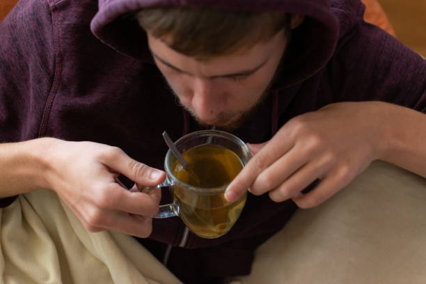 Sick young man drinking tea at home
