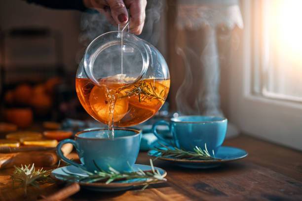 Pouring hot herbal tea into cups