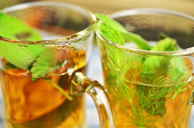  Two glass cups of herbal tea with fresh green leaves